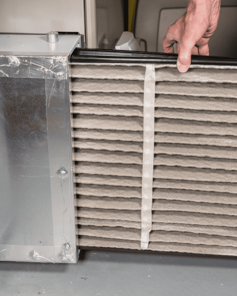 Technician replacing a furnace filter in Washington Park, CO with Van Genderen Heating & Air Conditioning to prevent costly repairs.